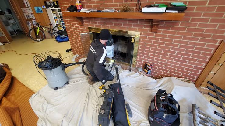 A fireplace work area with protective floor coverings, tools, and a vacuum